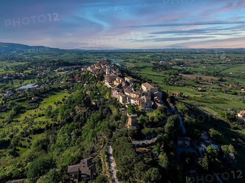 Breathtaking aerial view of Treia, Italy, showcasing historic architecture amid lush greenery and rolling hills under a clear blue sky, capturing the essence of Italian charm