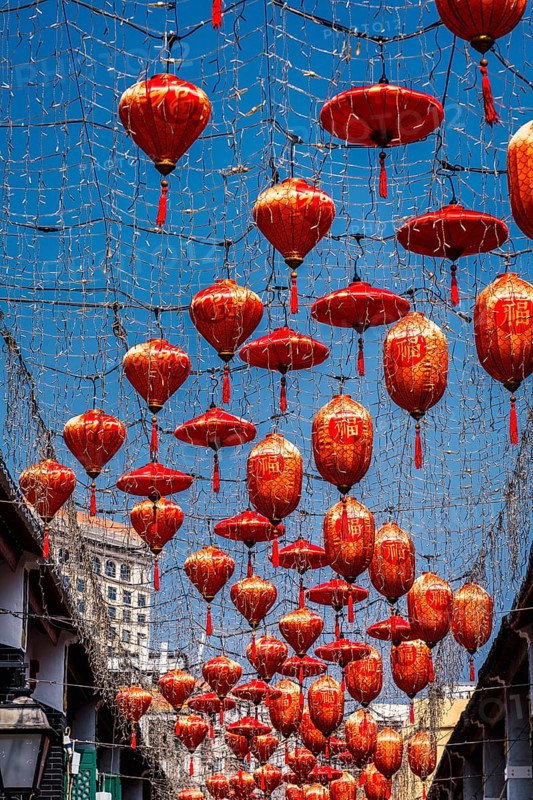 From below a captivating display of vibrant red lanterns adorned with Chinese characters, suspended under a blue sky in a street in Macau, creating a festive atmosphere
