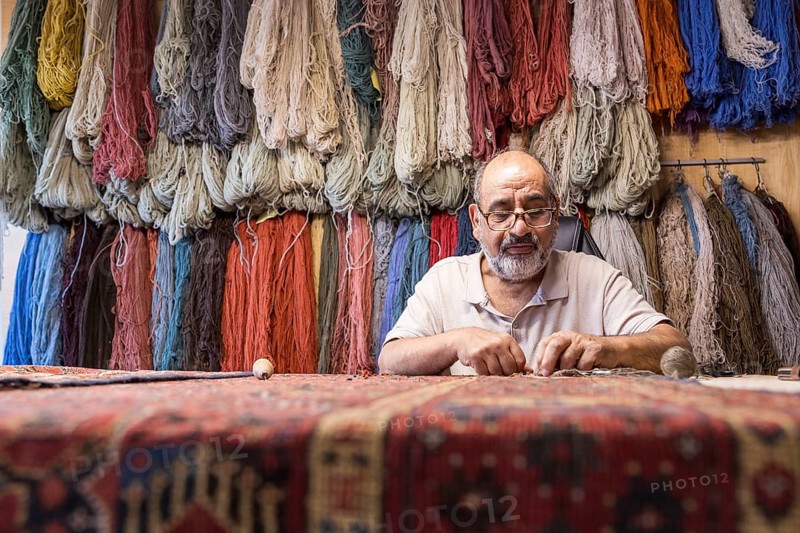 An Iranian master skillfully restores rare carpets in his well-equipped workshop in Salzburg, Austria, surrounded by colorful yarns