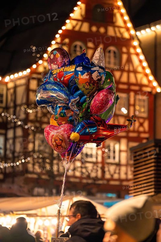 A colourful collection of balloons in front of traditional architecture at a lively Christmas market, Christmas market Calw, Black Forest, Germany