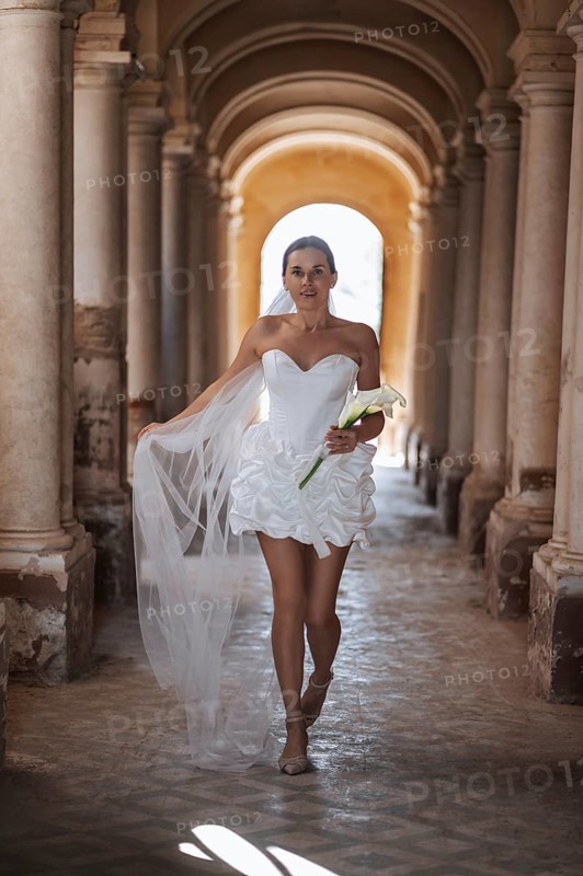 A bride in a stunning white gown gracefully walks down the aisle of the ancient villa in Treia, Macerata. The setting captures the timeless elegance of an Italian wedding