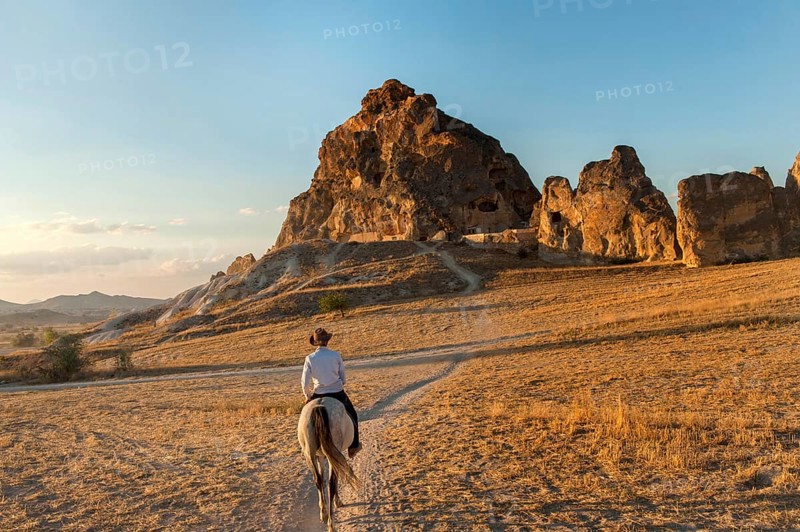 A local Turkish man rides a horse through the volcanic landscape of Cappadocia, known as the land of beautiful horses, Turkey
