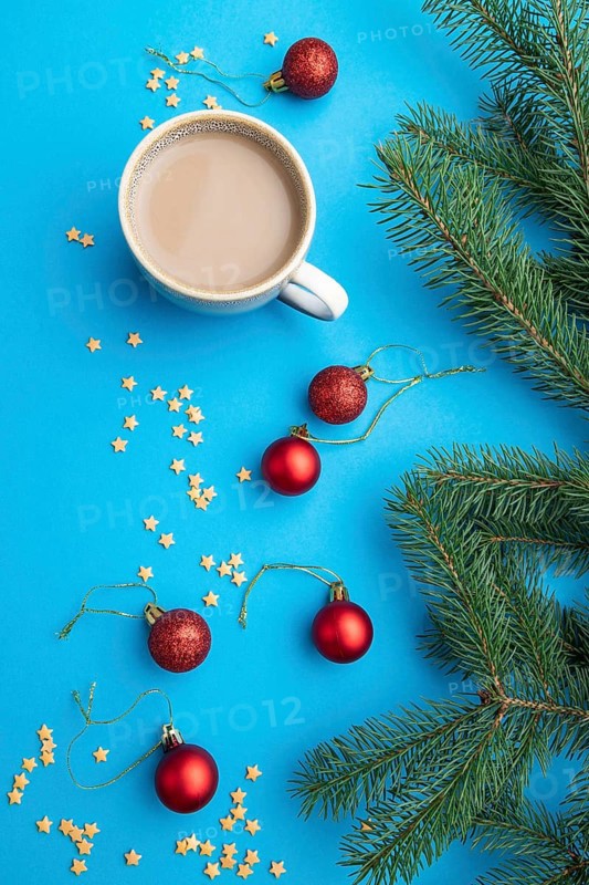 Christmas or New Year composition. Decorations, red balls, fir and spruce branches, cup of coffee, on a blue paper background. Top view, close up, flat lay