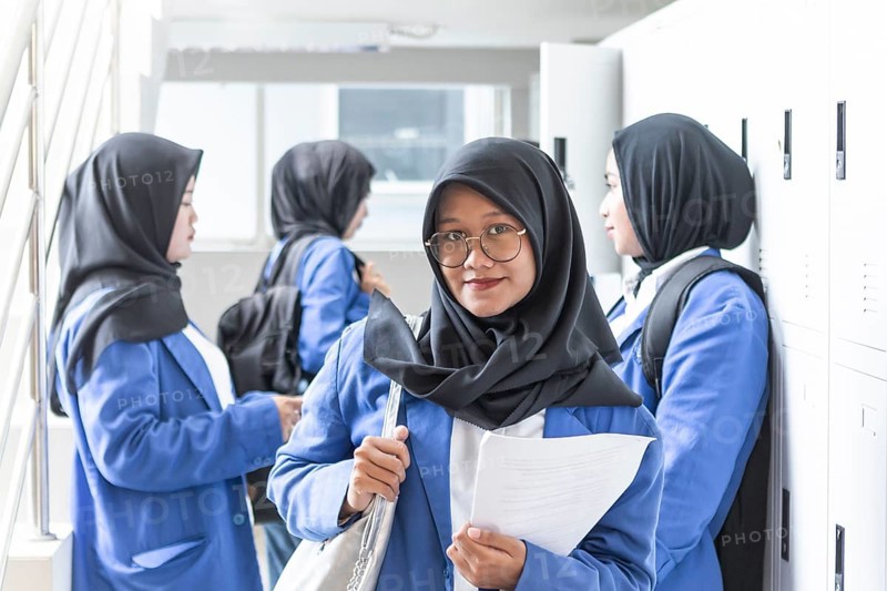 A group of Muslim students in blue uniforms and hijabs gathers in a school hallway, symbolizing education, diversity, and cultural unity as they prepare for classes