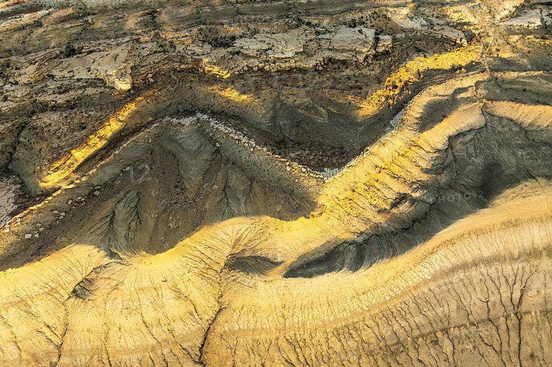 Aerial view of Utah's golden sandstone desert displaying intricate patterns and rich textures. The rugged landscape reveals nature's artistry and geological history