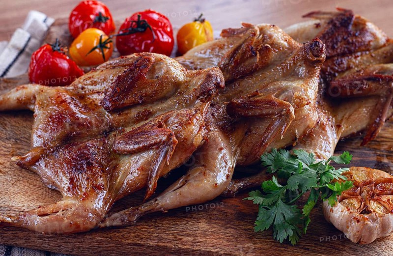 Grilled quail meat, on a wooden chopping board, tobacco, in the oven, with spices, homemade, without people