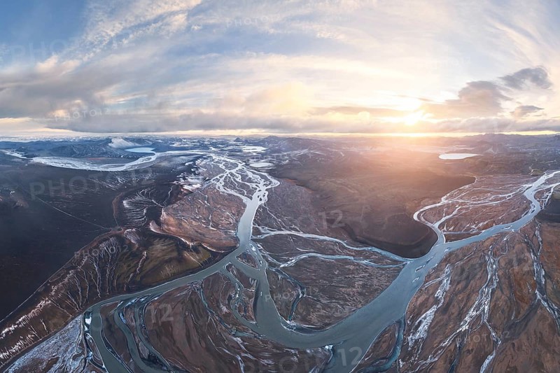 Aerial view of Iceland's highlands, showcasing intricate river networks weaving through rugged terrain at sunset. A breathtaking example of nature's artistry