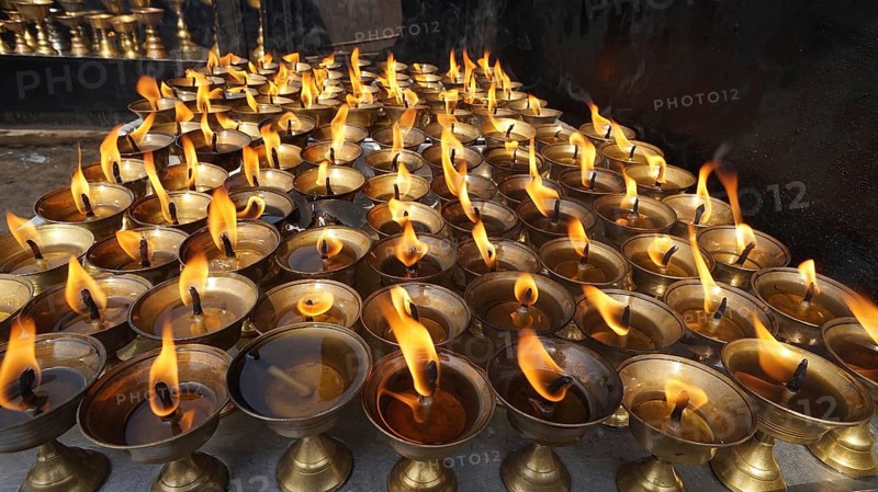 Many burning oil lamps produce a warm, glowing ritual light, Bodnath, Kathmandu, Nepal