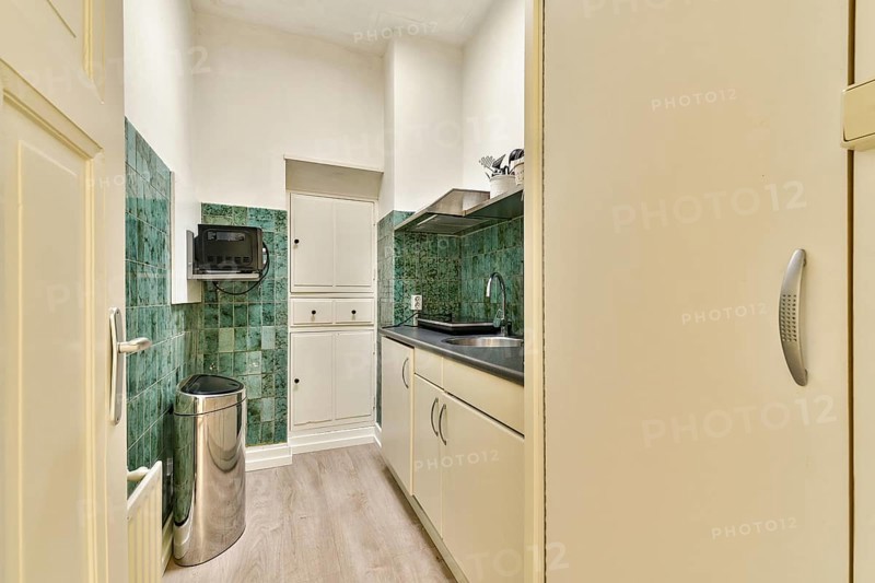 A sleek, modern kitchen showcases minimalist design with green tiled walls, clean cabinetry, and stainless steel appliances, creating an inviting cooking space