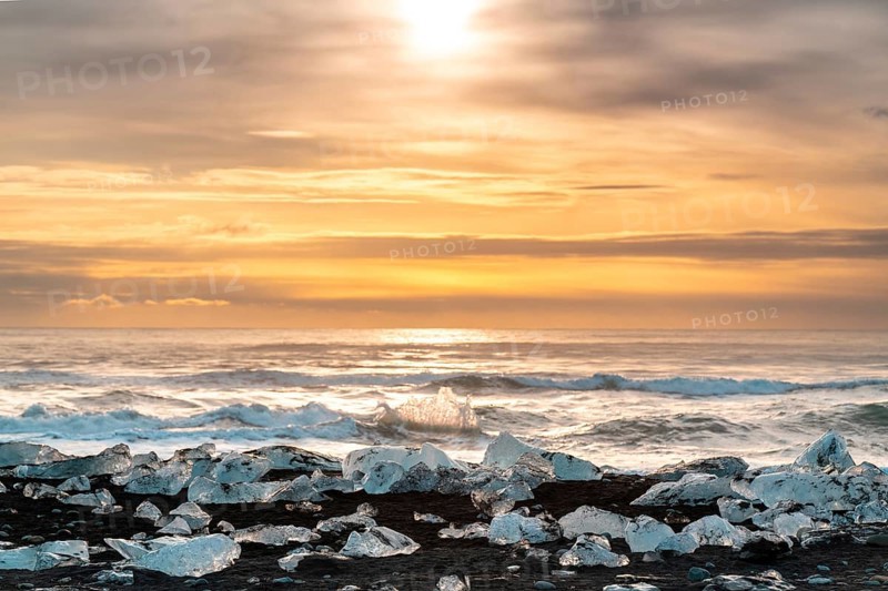 Captivating sunrise over Diamond Beach, Iceland, with ice fragments glistening on black sands and waves crashing gently, capturing the essence of serene Arctic beauty