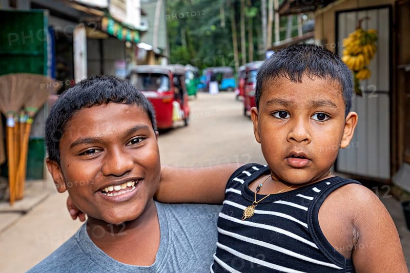Two young boys pose happily on a street, one smiling, the other seriously, A family in Ratnapura in Sri Lanka