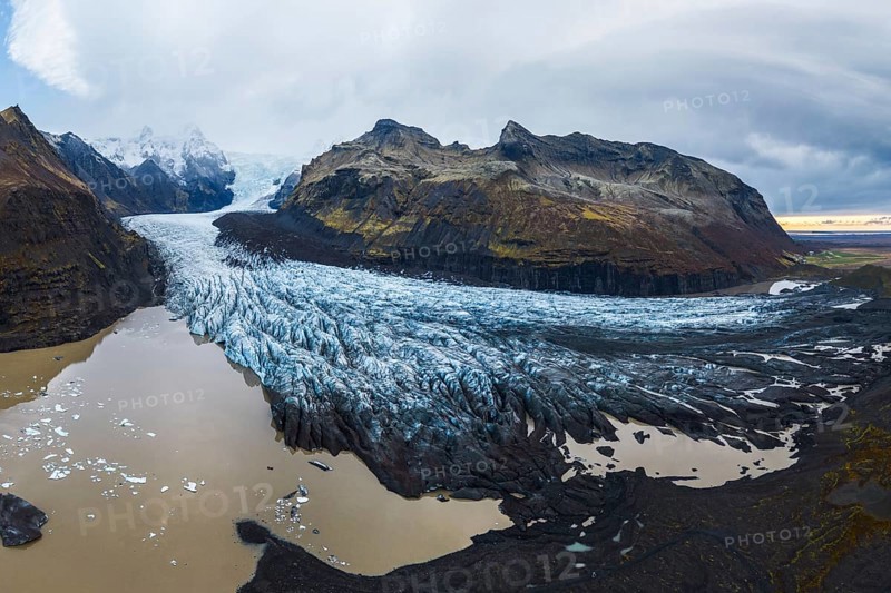 A panoramic shot of the vast Vatnajökull Glacier flowing between rugged mountains under a cloudy sky in Vatnajökull National Park, Iceland