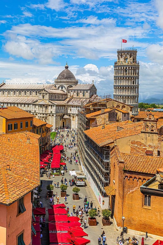 Above the rooftops of Pisa, behind the Cathedral of Santa Maria Assunta and the Leaning Tower, Via Santa Maria, Pisa, Tuscany, Italy