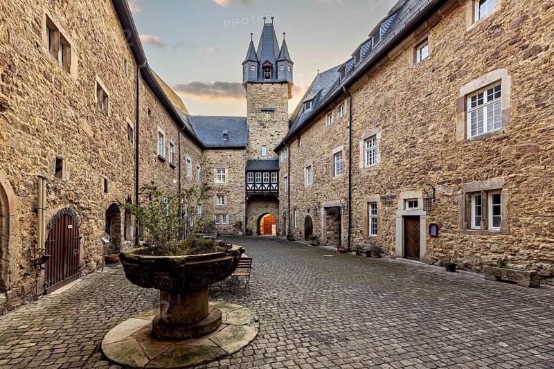 Inner courtyard with a view of a church tower and stone walls in the late afternoon light, The inner courtyard of Spangenberg Castle
