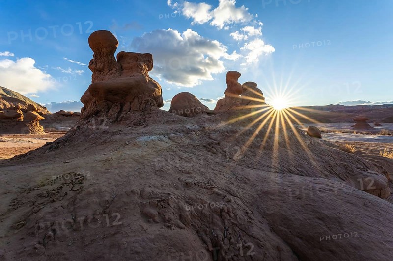 Dramatic sandstone formations in Goblin Valley State Park, Utah, USA, are illuminated by the setting sun. The natural rock sculptures create a stunning desert landscape