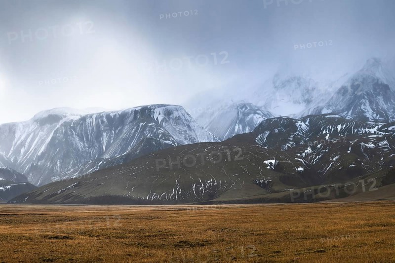 Experience the breathtaking beauty of Iceland's Highlands, featuring vast plains and majestic snow-capped mountains under a moody sky. Perfect for nature enthusiasts and photographers