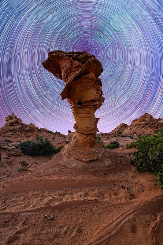 A mesmerizing view of swirling star trails in the night sky above a unique rock formation in a desert landscape, capturing nature beauty and the wonders of the universe in Coyote Buttes, Arizona