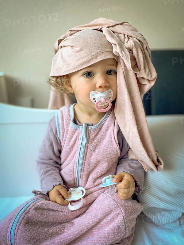 Child in pyjamas with dummy and scarf, lovingly and playfully depicted
