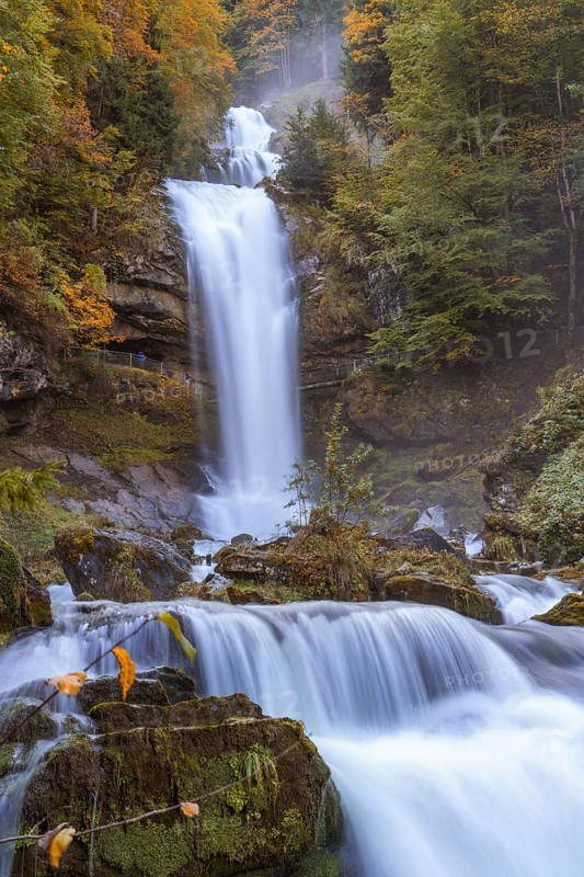 Rushing waterfall surrounded by autumnal forest and moss-covered stones, Grandhotel Giessbach, Lake Brienz, Switzerland