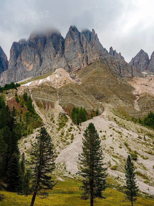 Geisler peaks rise above the rock layers into the cloudy sky, Villnöss Valley, Sass Rigais, Dolomites, South Tyrol, Italy
