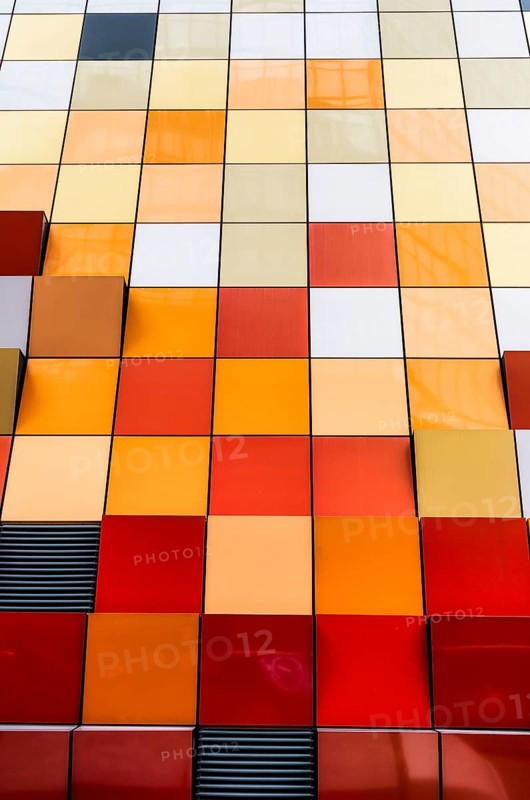 Close-up view of a vibrant and multi-colored tiled facade of a building in Hong Kong. The image showcases a spectrum of colors arranged neatly in squares, offering a modern architectural aesthetic