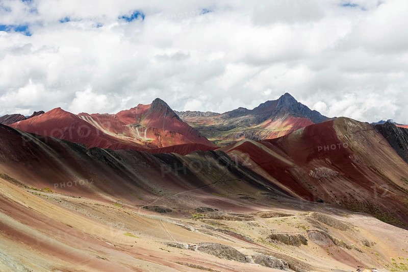 A remarkable landscape of Vinicunca, known as the Rainbow Mountain, featuring striking naturally colored mineral layers under a dynamic sky in Peru