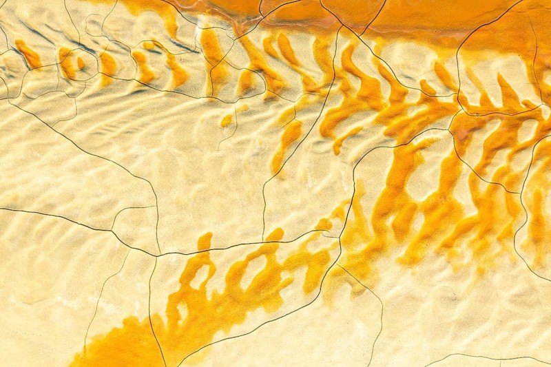Aerial view of textured golden mud patterns, creating abstract and organic designs across a landscape