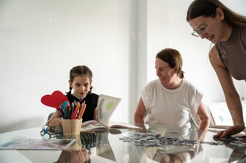 A joyful family moment with a girl with a tracheostomy engaging in art and puzzles, surrounded by supportive family members, showcasing love and creativity