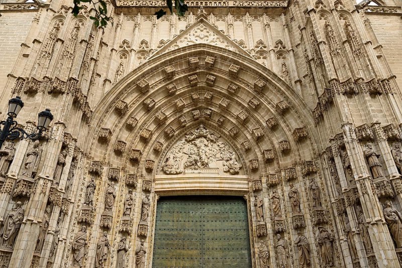 Elaborately decorated Gothic entrance door with detailed architectural elements, Seville, Andalusia, Spain
