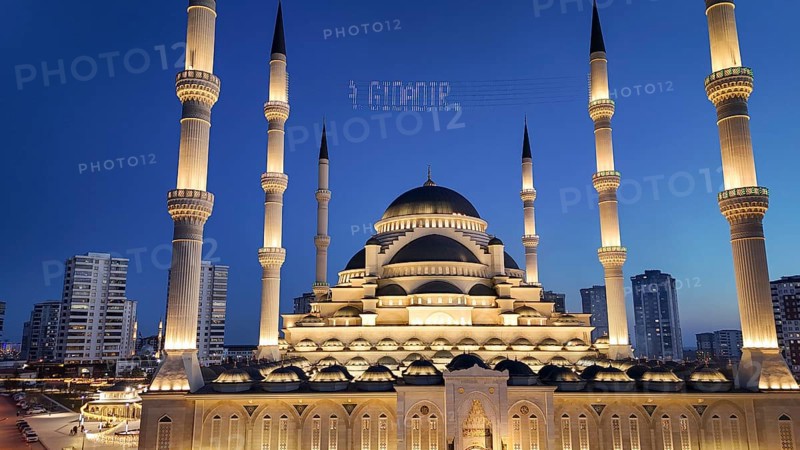 Aerial view captures hundreds of Muslims gathered at long tables for a communal Iftar meal in a festively decorated square outside a large mosque in Gaziantep, Turkey on March 11, 2026, Gaziantep, Turkey