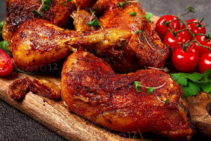 Grilled fried chicken legs, served with fresh cherry tomatoes, and herbs, on a wooden chopping board, homemade, no people