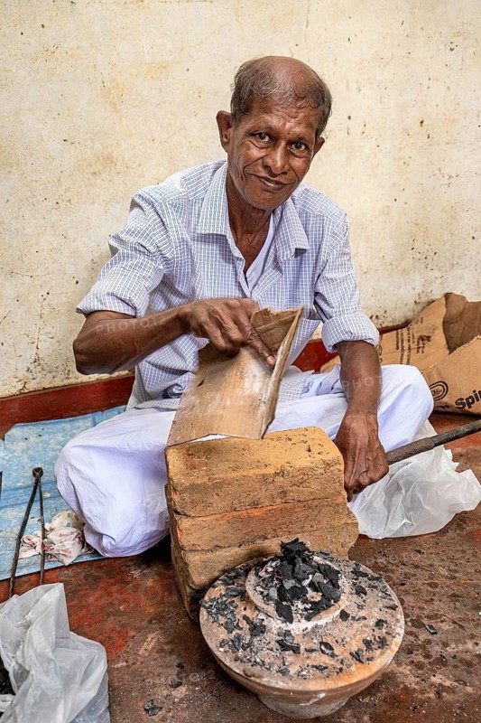 Elderly man works with bricks and coal in traditional clothes, a man burns sapphires in a small oven in the town of Ratnapura in Sri Lanka