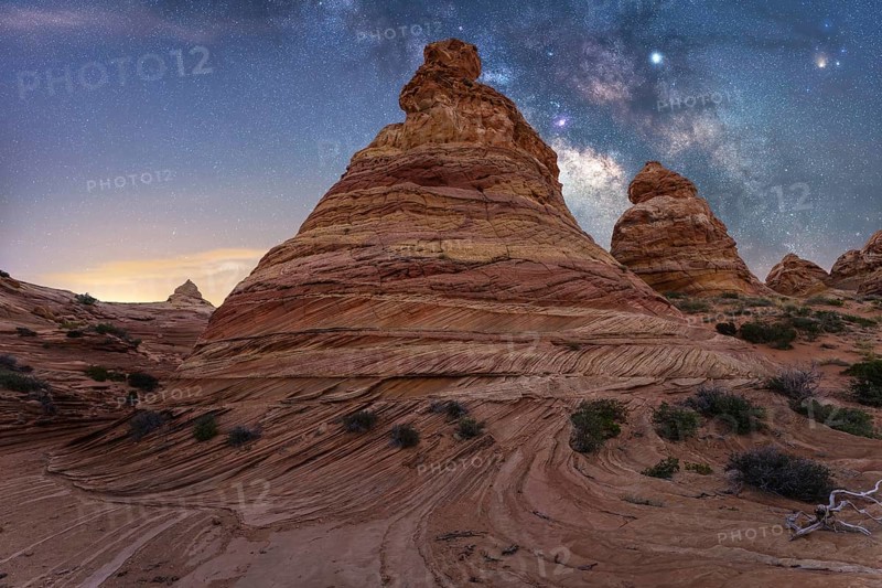 Scenic view of striking rock formations with swirling patterns under a mesmerizing starry night sky, showcasing the beauty of nature artistry and cosmic wonder in Coyote Buttes, Arizona