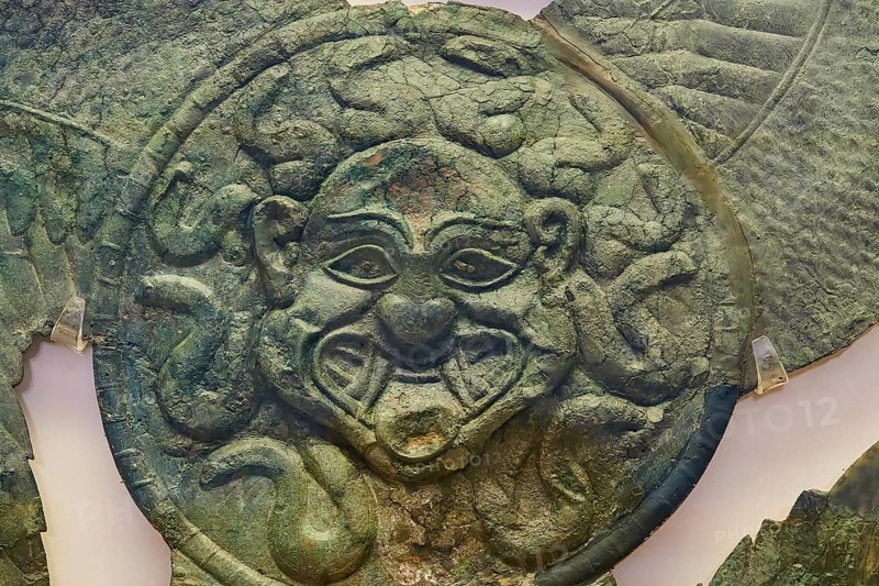 Winged gorgoneion acroterion, roof decoration from the Temple of Hera, an antique metallic face with decorated details and green patina, Olympia Archaeological Museum, Ancient Olympia, Olympia, Peloponnese, Greece
