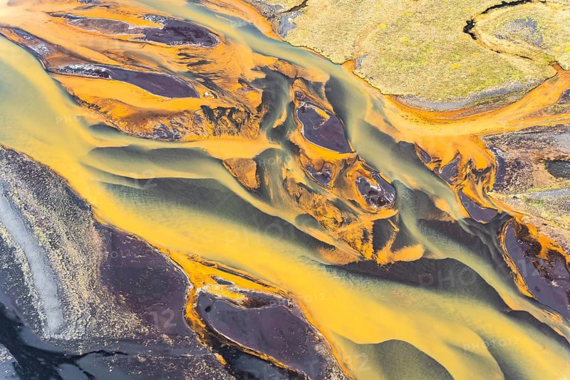 Stunning aerial capture of Iceland's golden rivers winding through vibrant landscapes, showcasing a mixture of colors and natural patterns