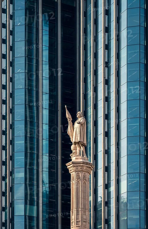 A striking display of architectural contrast in Colon City, Panama, showing a historic statue against the backdrop of sleek, modern glass skyscrapers
