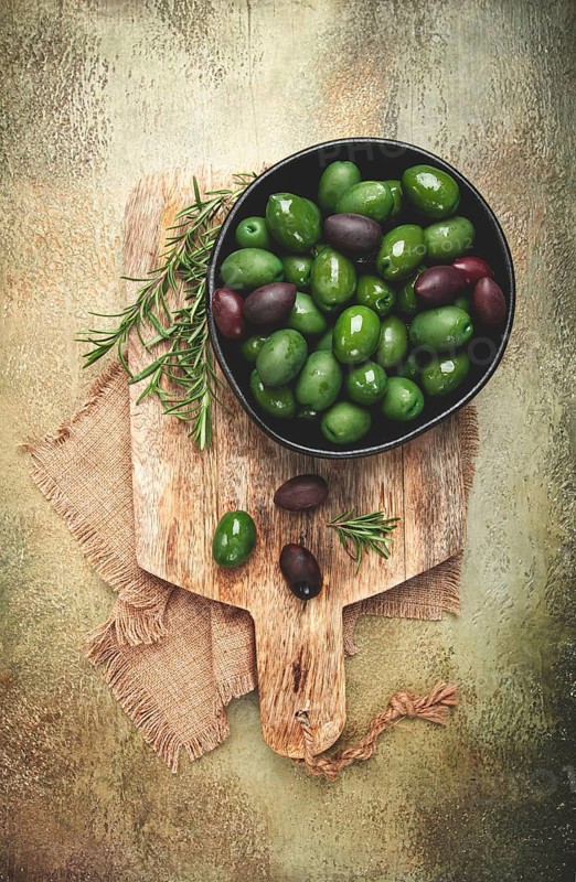 Chalkidiki olives, classic Greek green olives, in a bowl on a cutting board, top view, without people