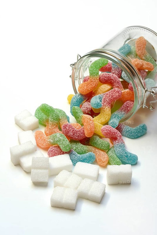 Lots of colorful jelly sweets in glass containers and sugar cubes, sugar consumption