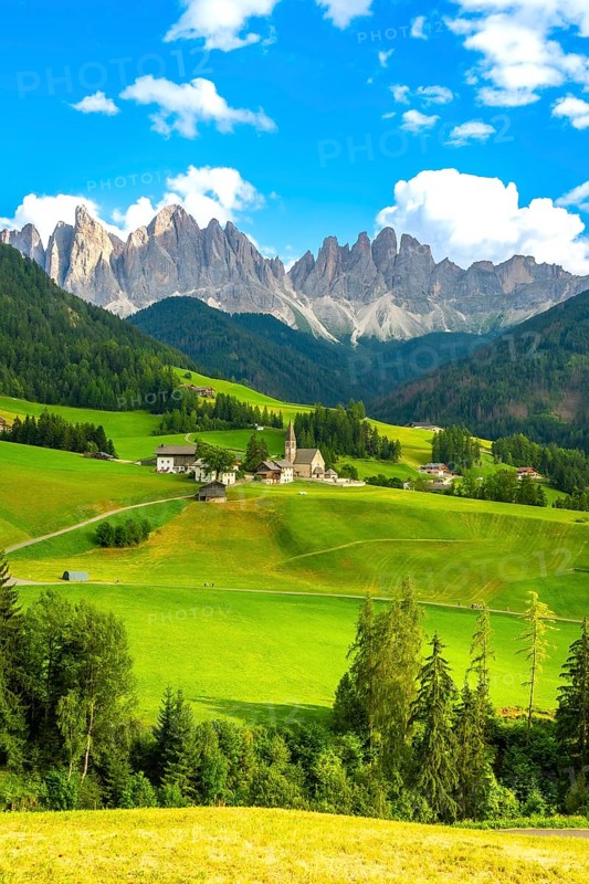 Green meadows and santa maddalena church under the odle mountain group in the italian dolomites during a sunny summer day