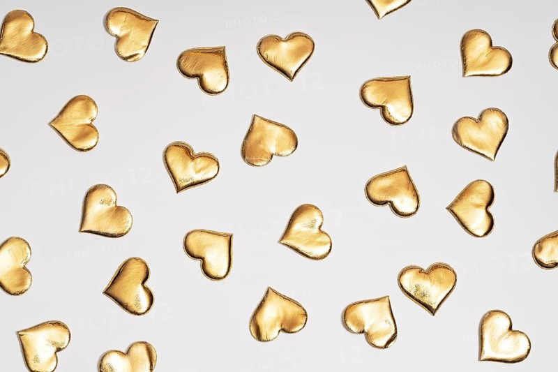 Numerous golden heart shapes artistically arranged on a plain white surface, symbolizing love and St. Valentine's Day. Ideal for themes related to romance and special occasions