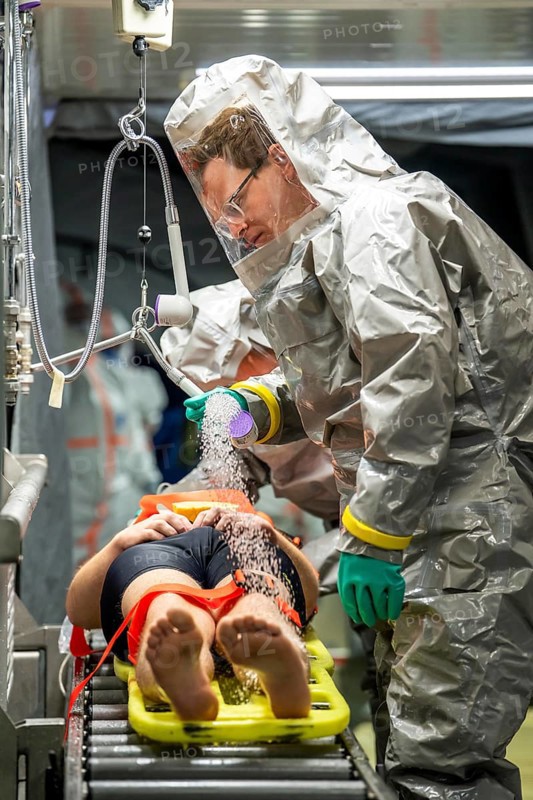 Decontamination of injured persons after an assumed accident involving hazardous substances, fire brigade and aid organisations practise setting up and operating a decontamination station, injured persons are sighted and then washed in a special shower tent to remove possible hazardous substances and chemicals in order to avoid further injuries, the emergency services wear special, ventilated protective suits, large-scale exercise by the Essen fire brigade