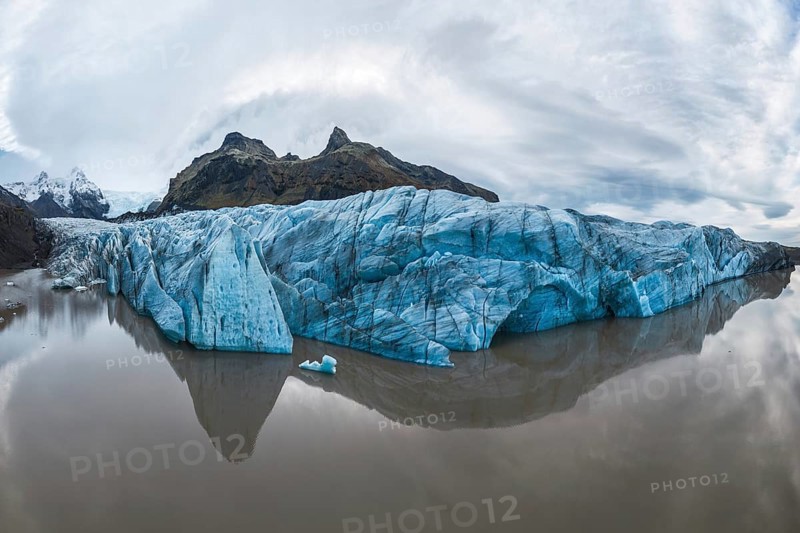 Captivating view of the expansive Vatnajökull Glacier, reflecting in calm waters at Vatnajökull National Park, Iceland, showcasing nature's tranquility and grandeur
