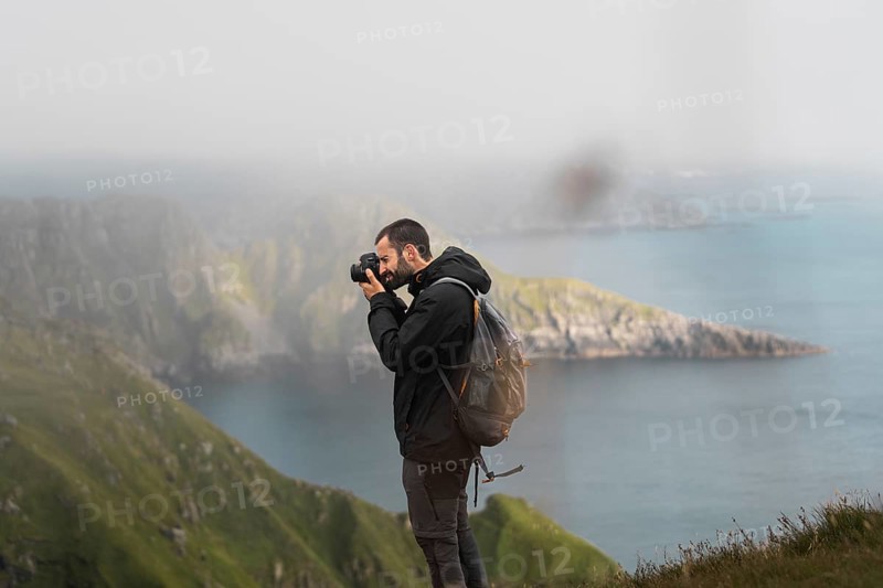 A traveler captures breathtaking views of Norway's rugged coastline Adventure, exploration, and photography during an outdoor trek, with the essence of freedom