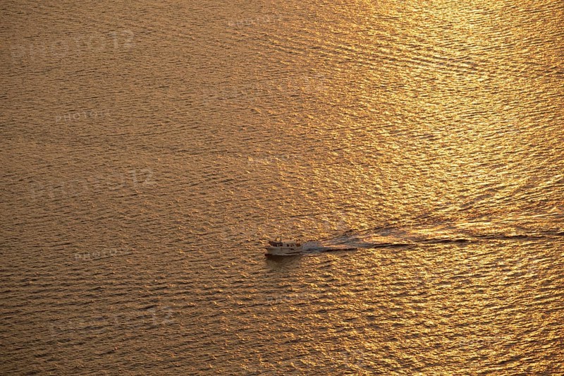 A small boat glides through the shimmering golden waters of the Mediterranean Sea at sunrise, capturing the serene beauty of the Costa Blanca's tranquil coastal landscape