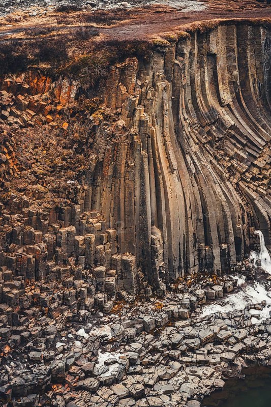 Stunning basalt columns at Studlagil Canyon, Iceland, display intricate geological formations. This natural wonder showcases unique textures and colors shaped by ancient volcanic activity