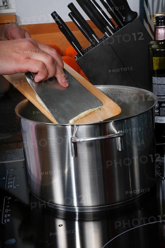 Swabian cuisine, preparation of herb spaetzle for roast beef, scraping spaetzle, spaetzle board, dough, cooking pot, savoury, salty, typical Swabian, home cooking, traditional cuisine, men's hands, food photography, studio, Germany
