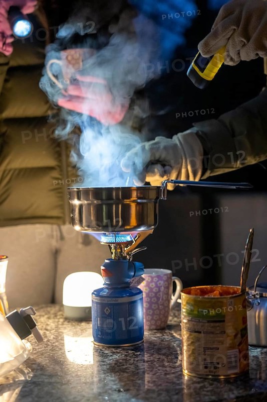 Symbolic picture blackout, extensive, prolonged power failure, in private surroundings, without electricity, heating, water, cooking, heating food and water with a gas-powered camping stove, on the balcony