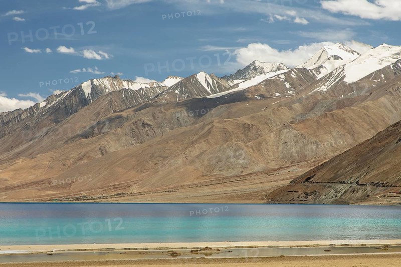 Beautiful view of Pangong Tso lake in Ladakh, India, with its brilliant blue waters set against the background of the majestic snow-capped Himalayan mountains under a clear sky