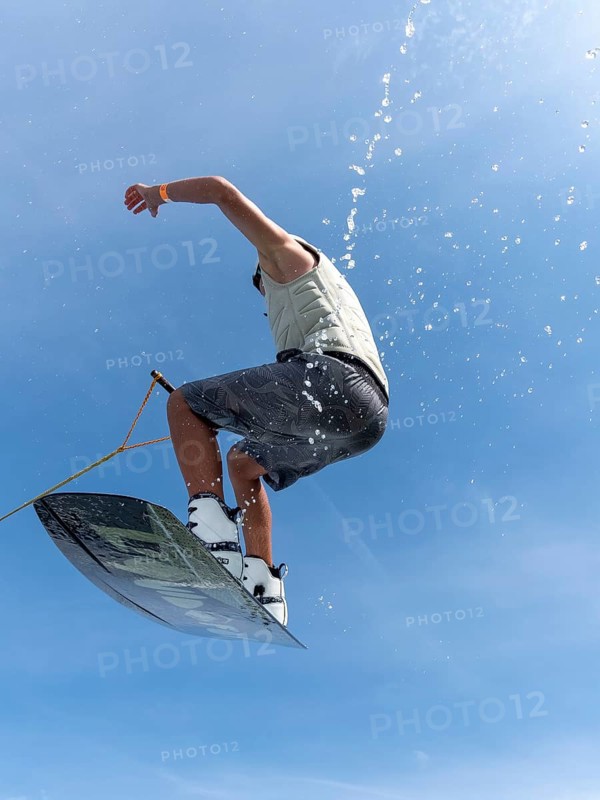 Young man jumping and flying with wakeboard, water sports and water skiing in the wakepark