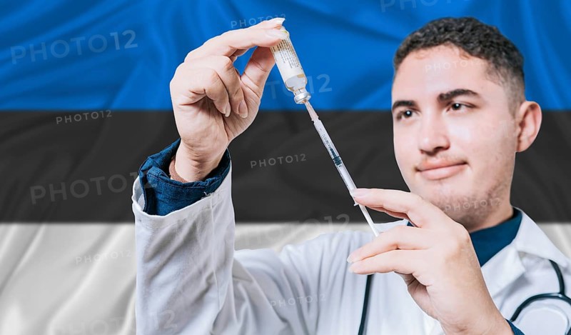 Doctor holding syringe on Estonia flag background. Medical professional holding syringe with Estonian flag in the background